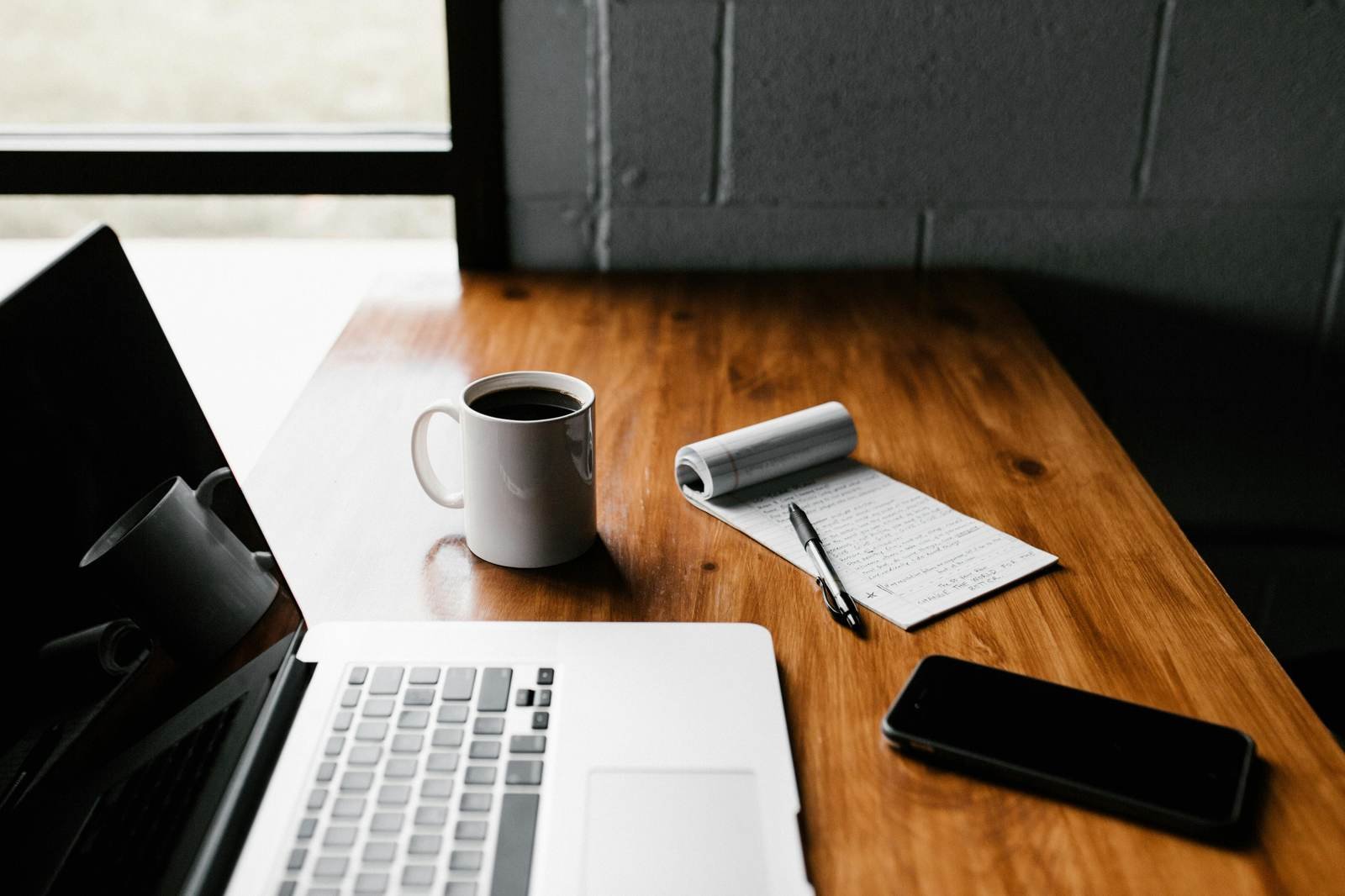 Ordinateur portable, tasse de café et carnet sur un bureau en bois